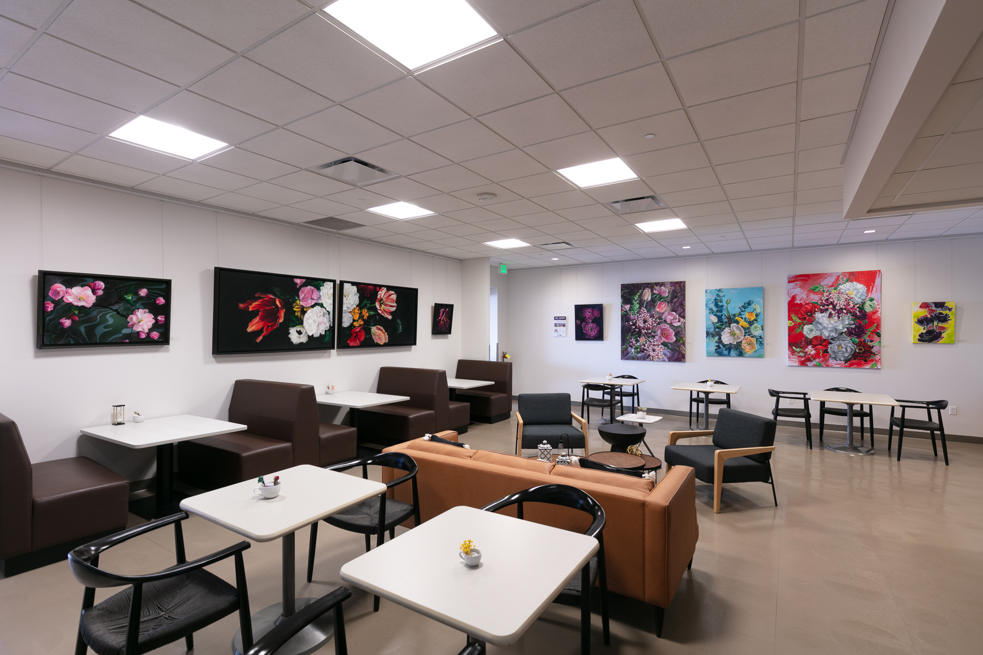 Bright cafe with floral art on walls, modern seating arrangement.