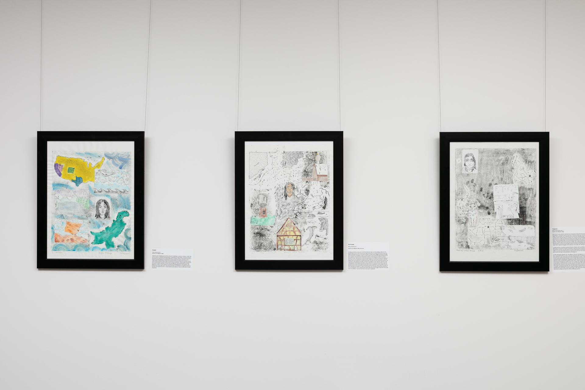Three framed artworks hung in a gallery, each featuring abstract designs and accompanied by descriptive labels.