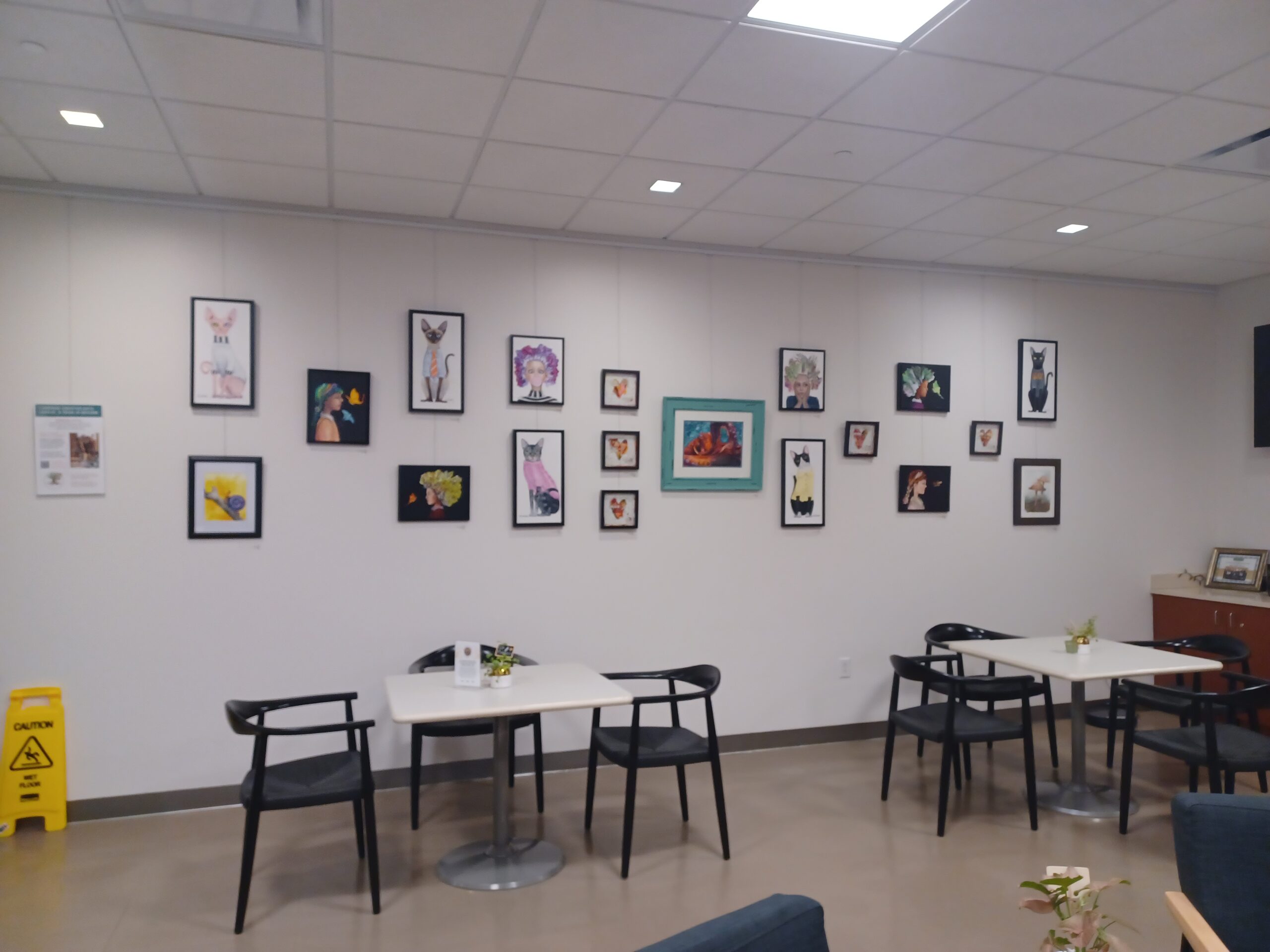 Art-filled lounge area with various cat-themed paintings on the wall.