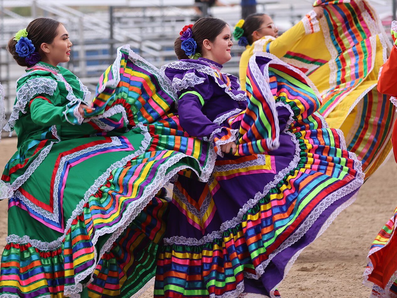 Women performing traditional dance in colorful, lace-trimmed dresses with vibrant patterns