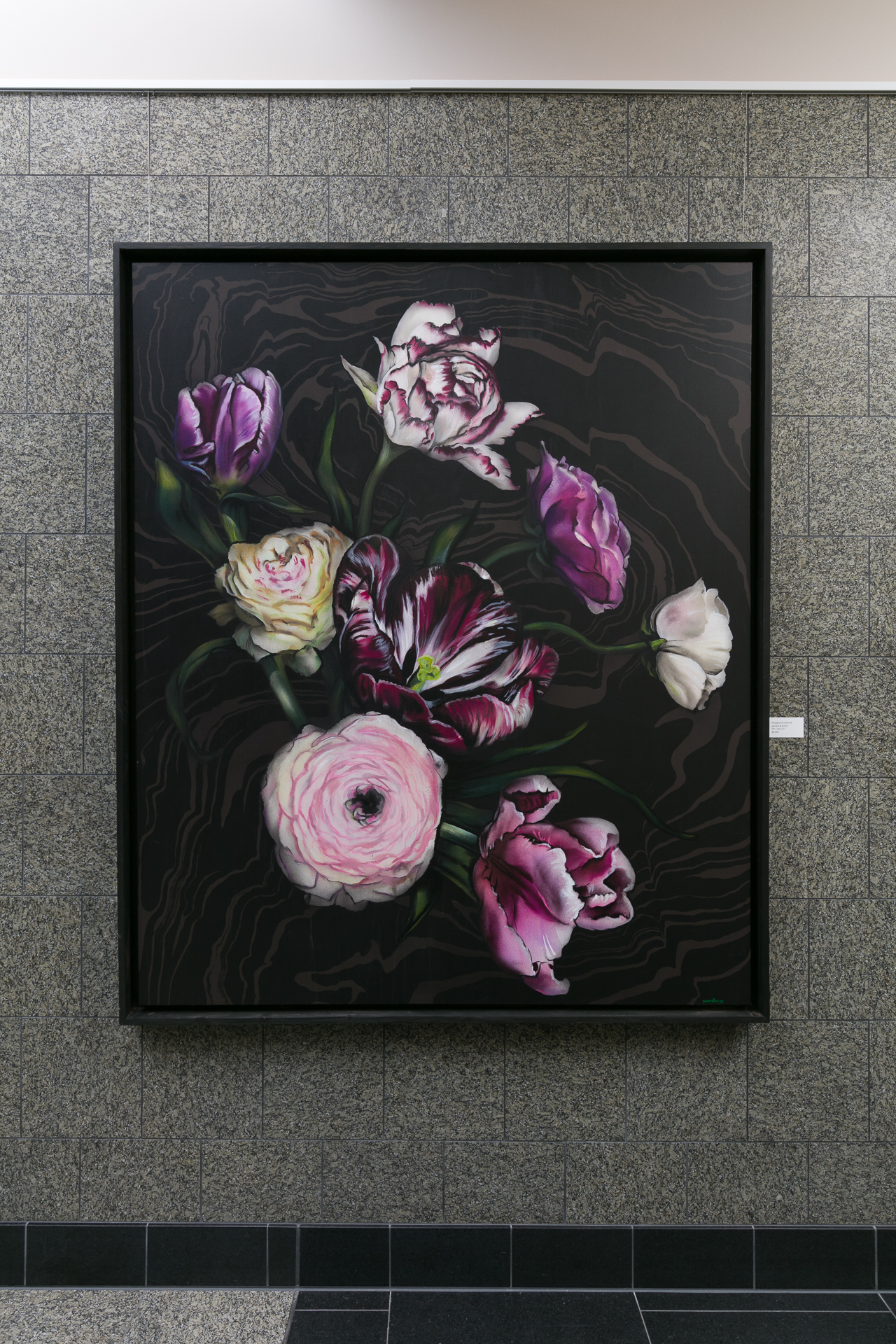 Framed floral painting with pink and purple flowers against a dark marbled background, mounted on a textured wall.