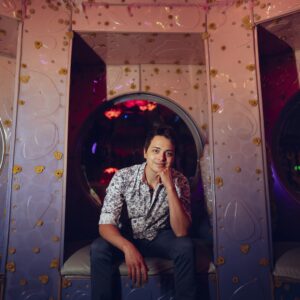 Brandon sitting in a colorful, decorated booth with a pensive expression