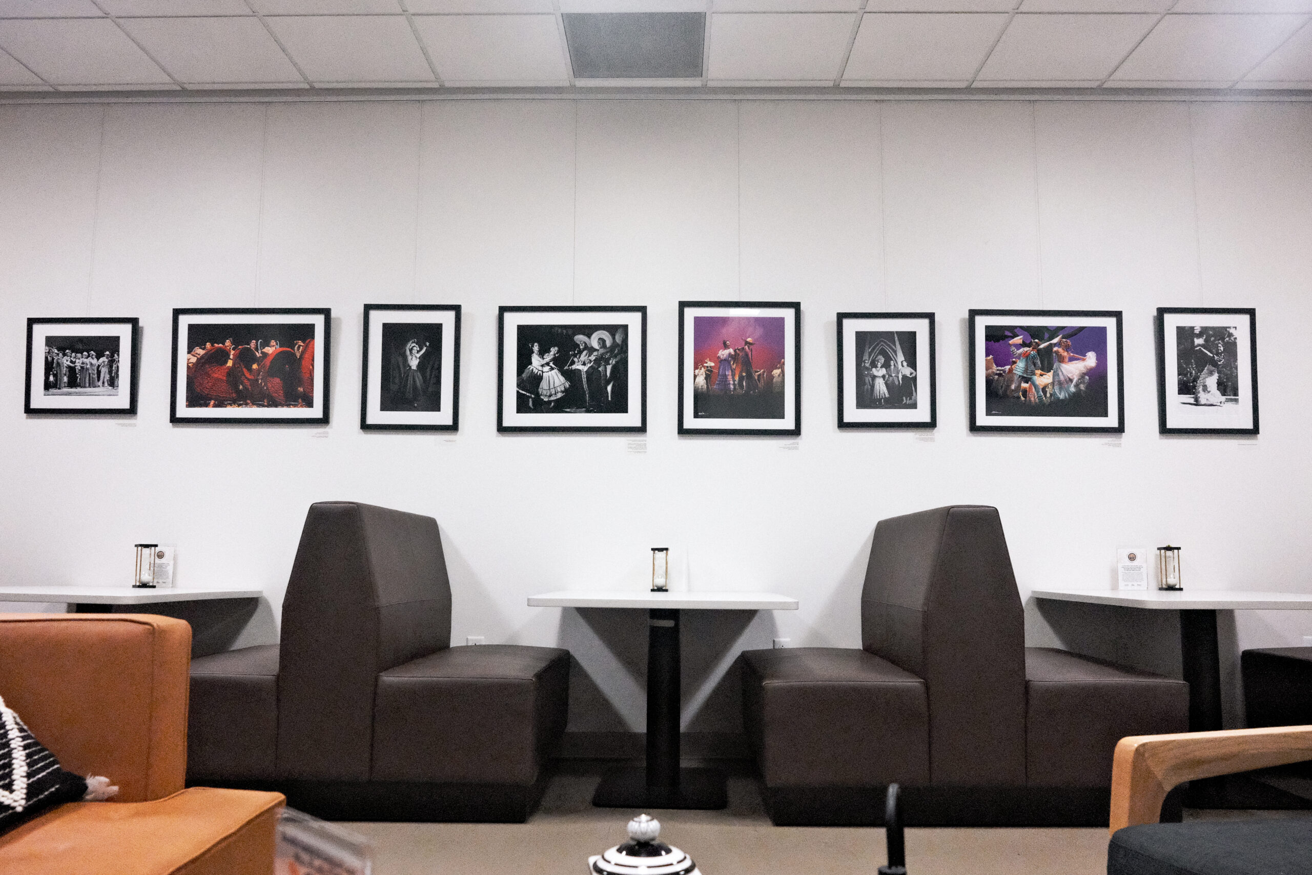 Cafe with two seating booths, framed photographs above, featuring various dramatic performance scenes on display.