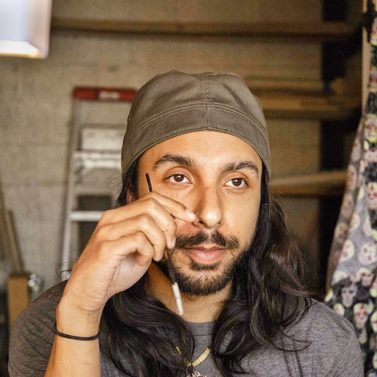 Cal Duran in a workshop holding a small brush, appearing thoughtful.