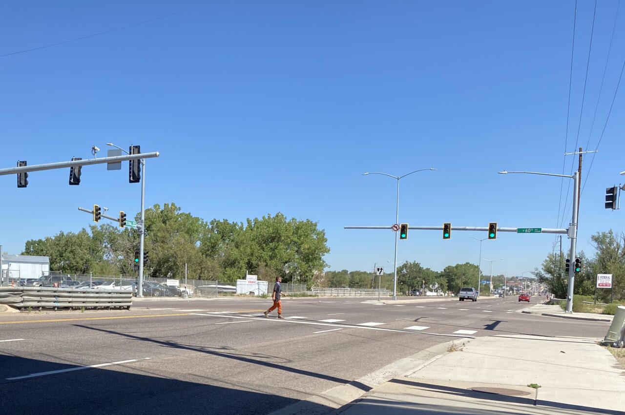 A person crossing a wide street with green traffic lights