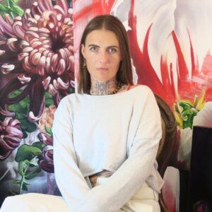 Grow-Love-1.jpg seated person with tattoos, colorful floral mural background