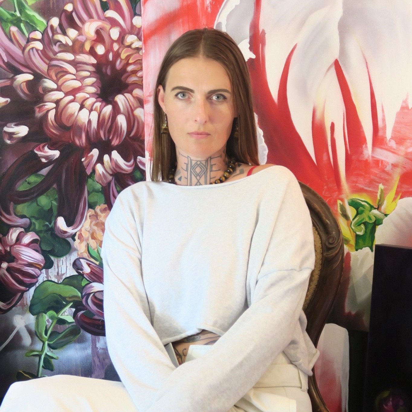 Grow-Love sits against vibrant floral mural, wearing light top.