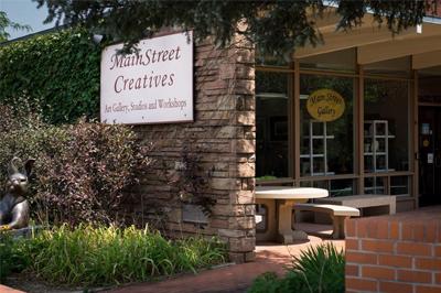 MainStreet Creatives building exterior with art gallery sign, green plants, and outdoor seating.