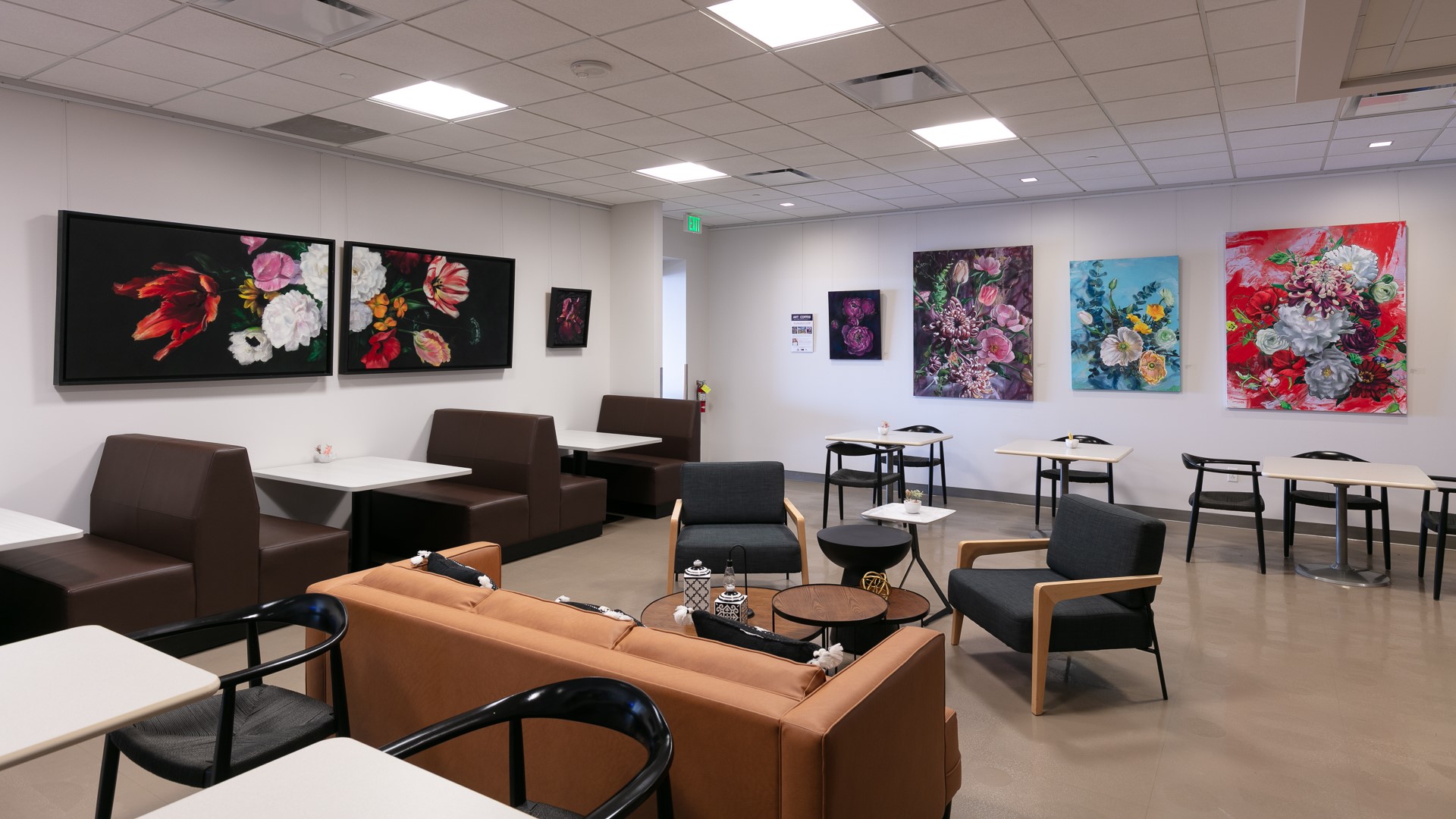 Cafe lounge with modern furniture and vibrant floral paintings on walls