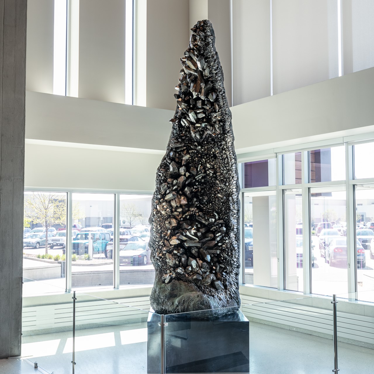 Large abstract sculpture resembling a jagged, textured column inside a bright atrium.