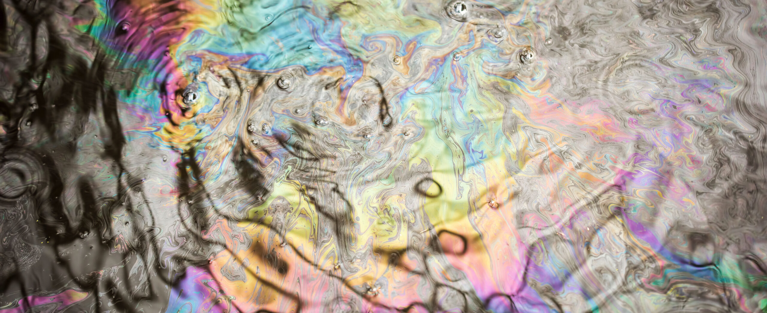 Colorful iridescent oil spill on water with swirling patterns