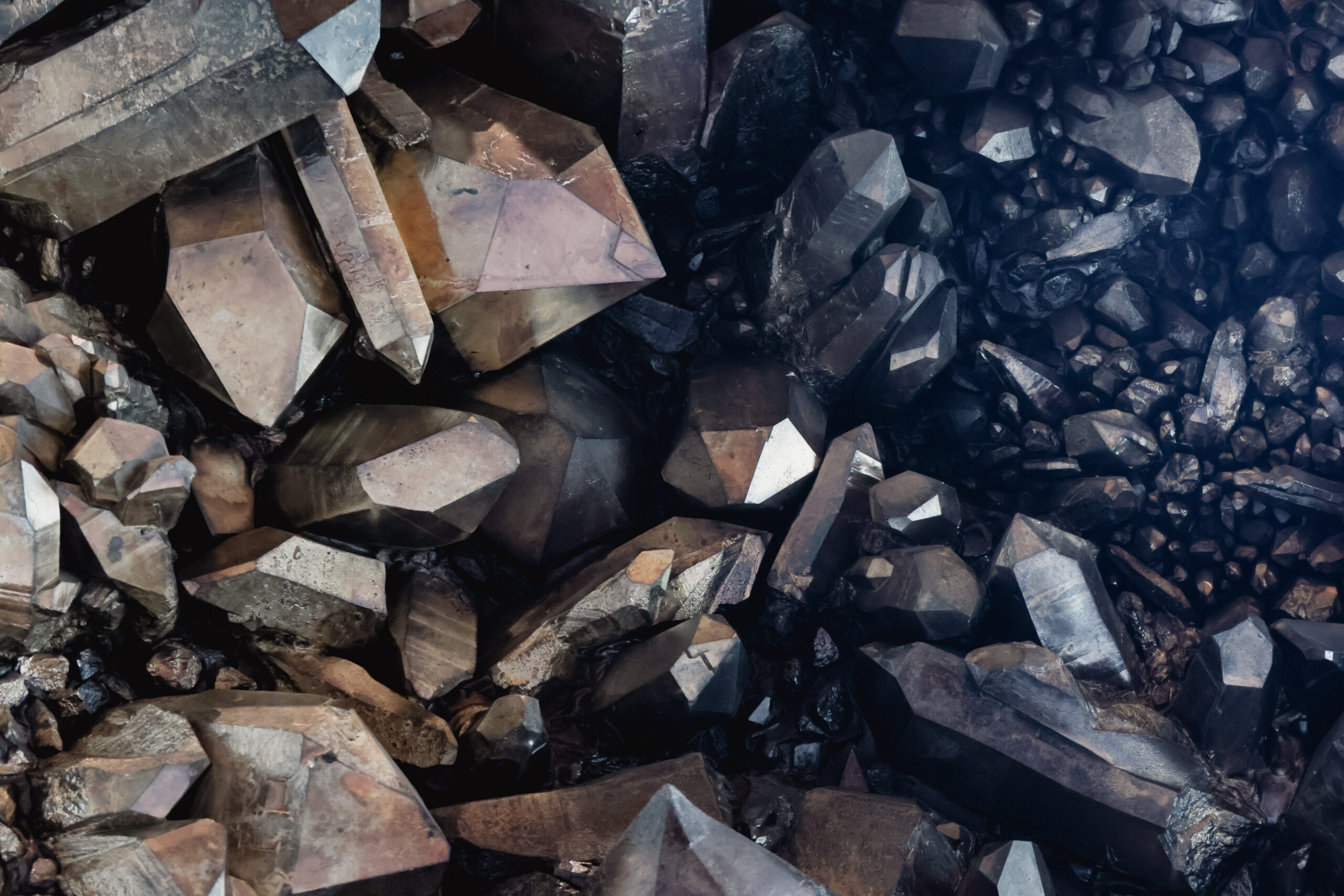 Cluster of large, shiny brown and gray crystals reflecting light.