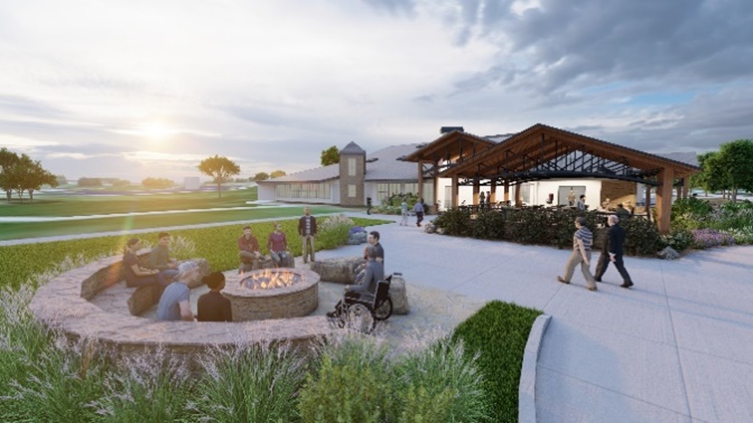 People gather around a fire pit at a park, evening light, grassy landscape, building in background
