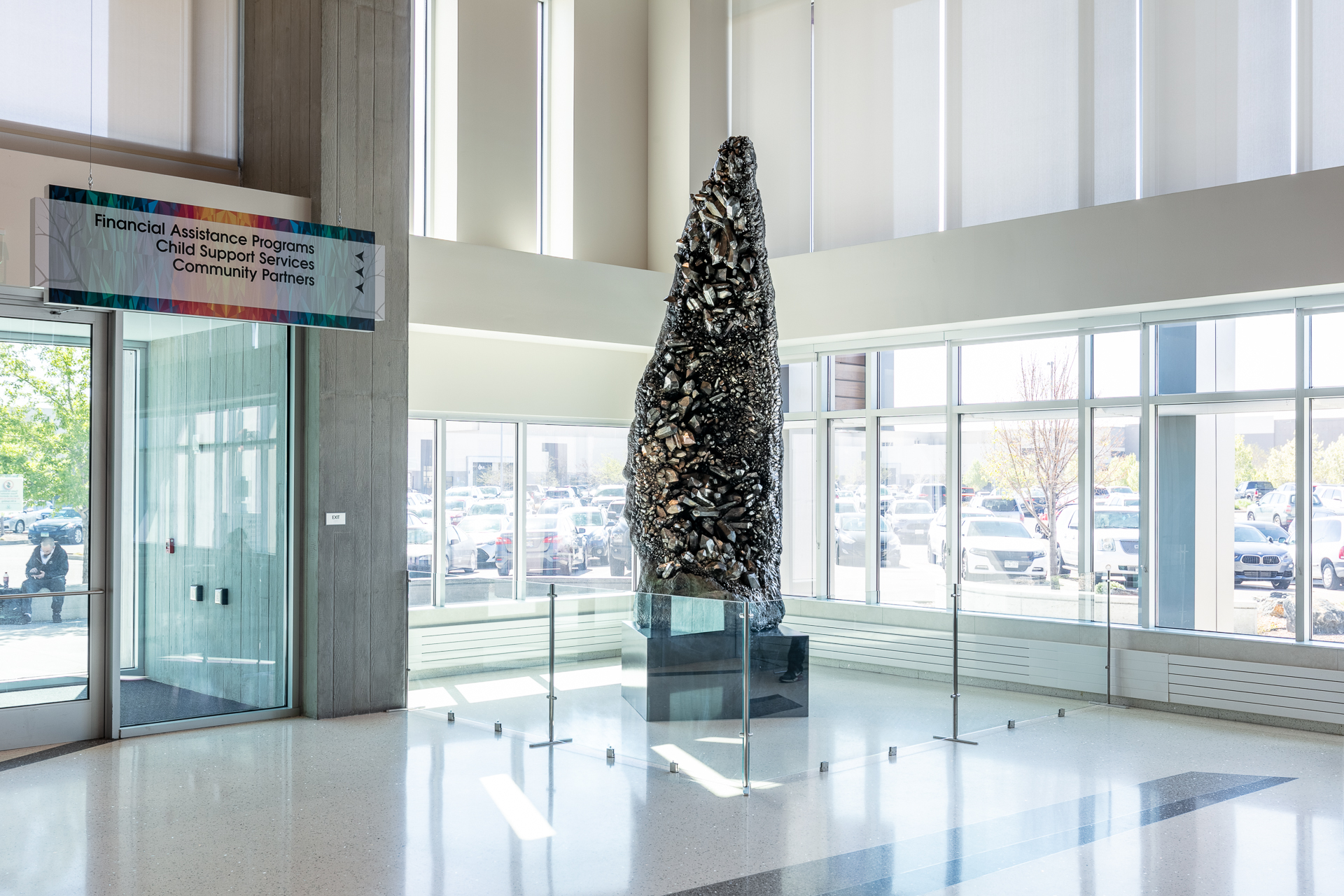 Large crystal sculpture in bright lobby with sign: "Financial Assistance Programs, Child Support Services, Community Partners"