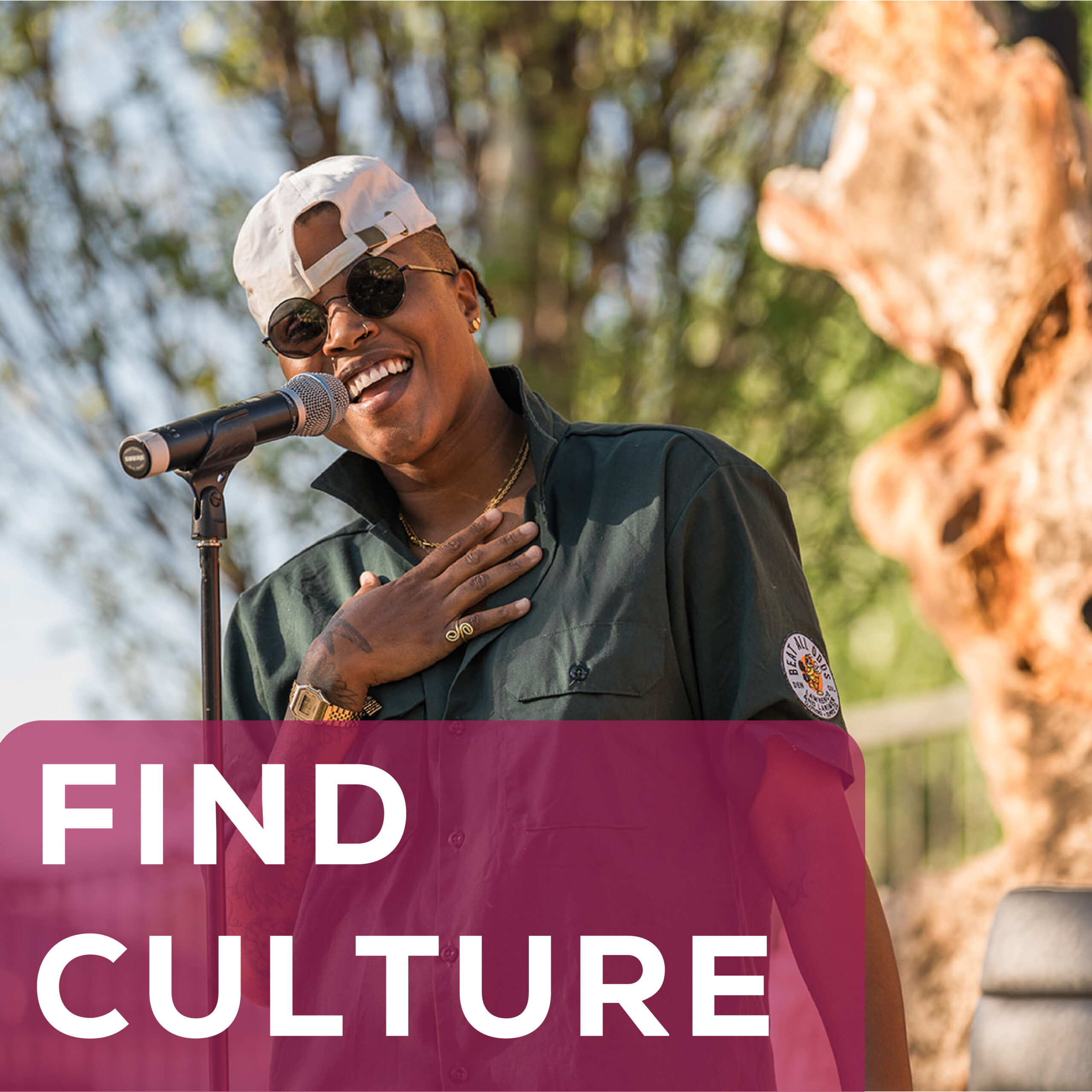 Person smiling and performing outdoors with microphone, text "Find Culture" in bold front.