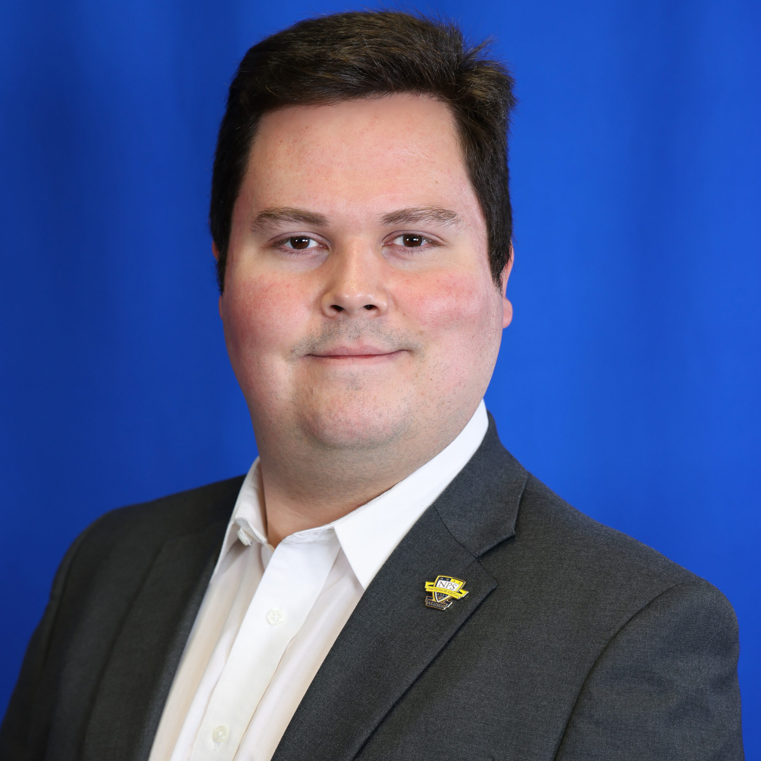 Lopez, wearing a suit, smiles slightly against a blue background.