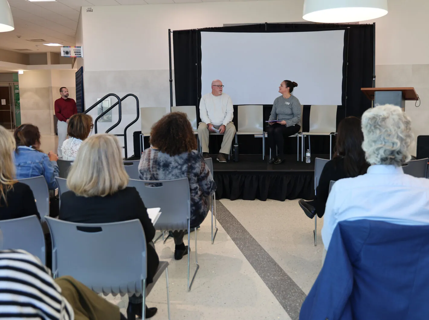 Audience watching a panel discussion with two people seated on stage