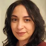 Sandra, smiling woman with long dark hair, neutral background