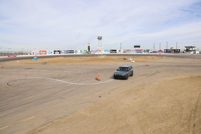 Car navigating an empty racetrack with surrounding advertisement banners.