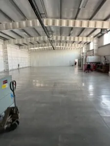 Large empty warehouse with office area and equipment cart.