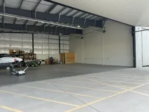 Partially open aircraft hangar with small airplane and storage shelves