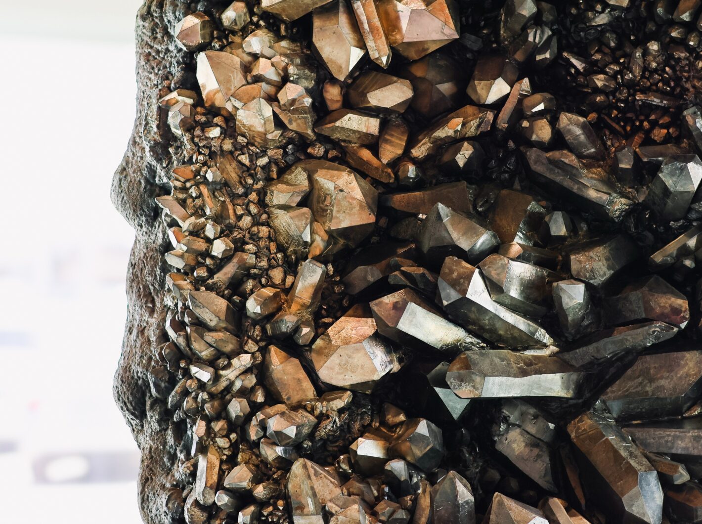 Close-up of a cluster of sharp, metallic brown crystals on rock surface