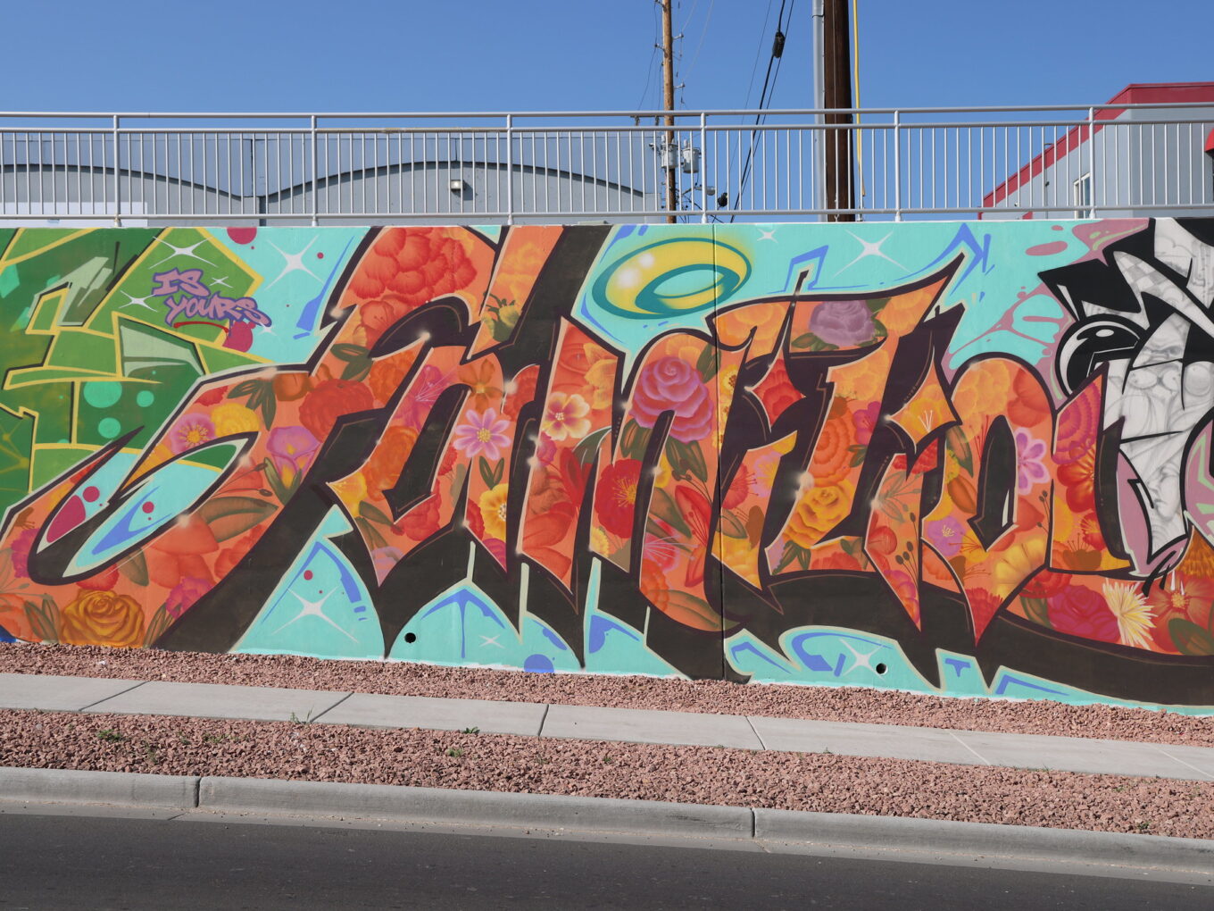 Colorful street art mural with floral patterns and text "Be Yourself."