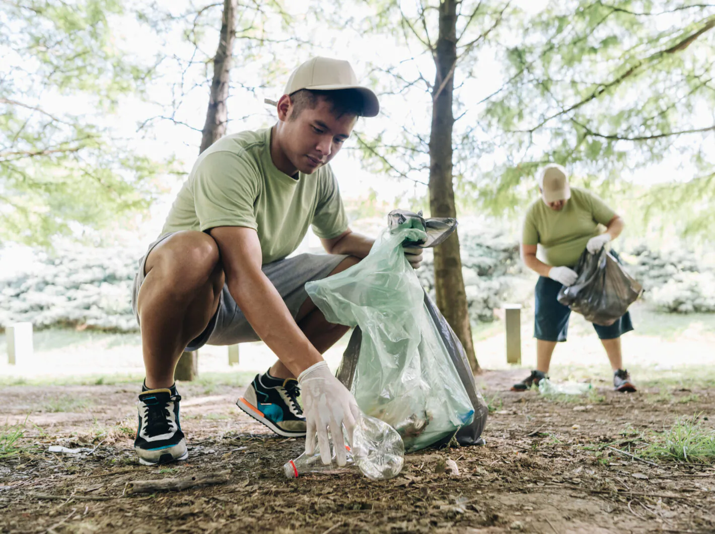 Young man volunteer collecting trash in public park