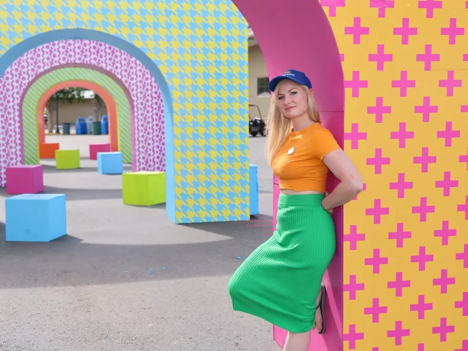 Person in colorful outfit posing by vibrantly patterned arches and blocks outdoors