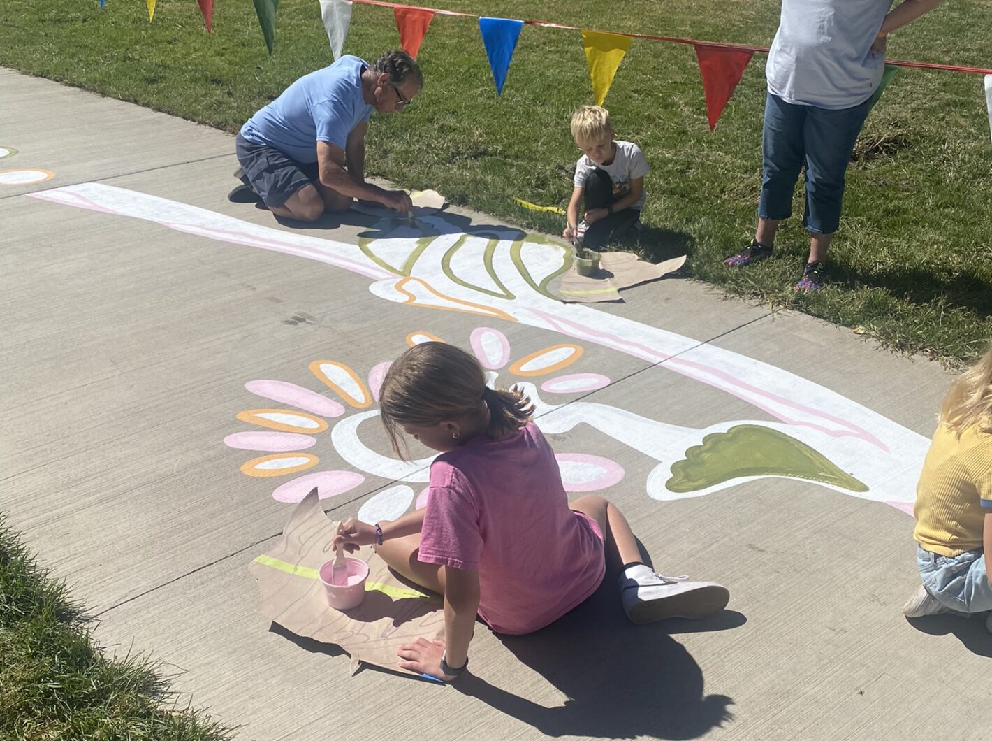 People painting colorful flower patterns on a sidewalk outdoors