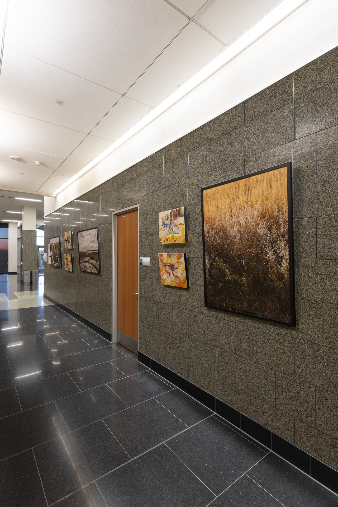 Art gallery hallway with framed paintings on a stone wall