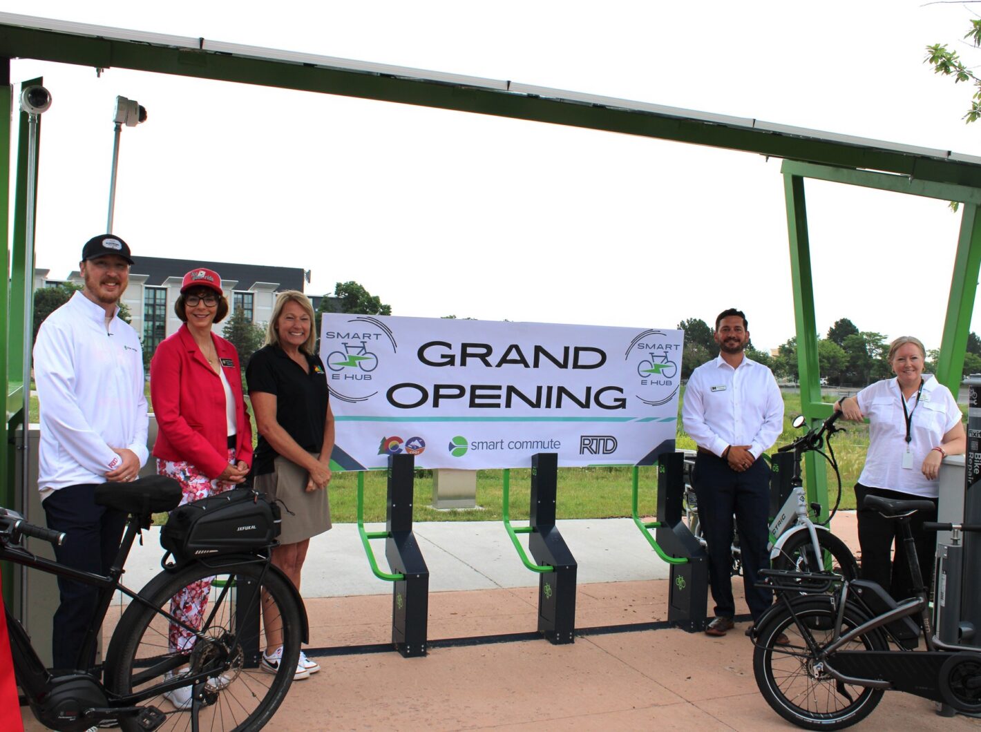 Five people stand by e-bikes at a Smart e-bike hub grand opening