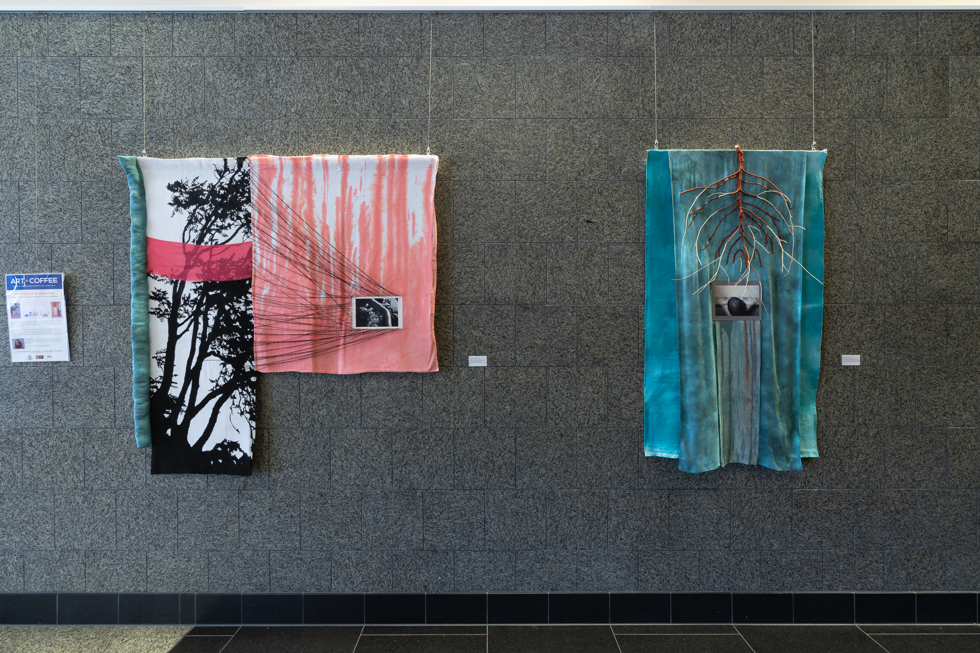 Two abstract textile artworks displayed on a gray wall, featuring tree silhouettes and textured patterns