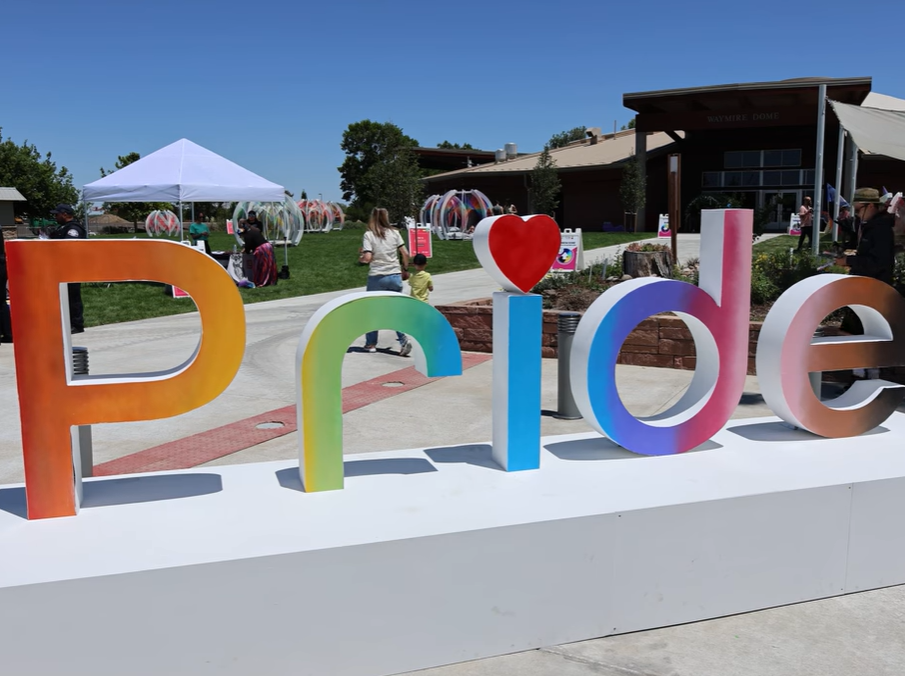 Pride display with colorful letters and heart, outdoor event setting