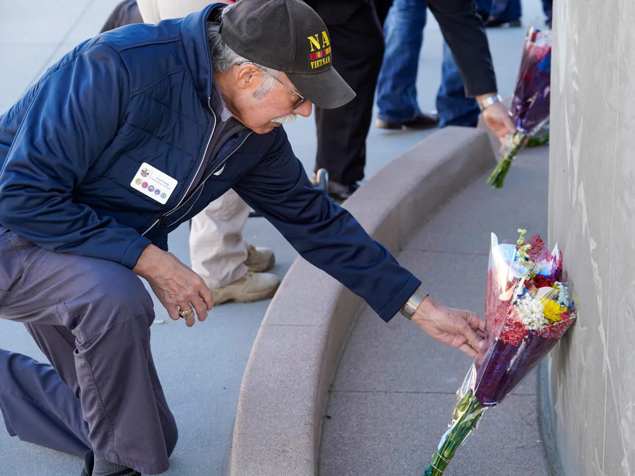 Veteran placing a flower at a memorial.